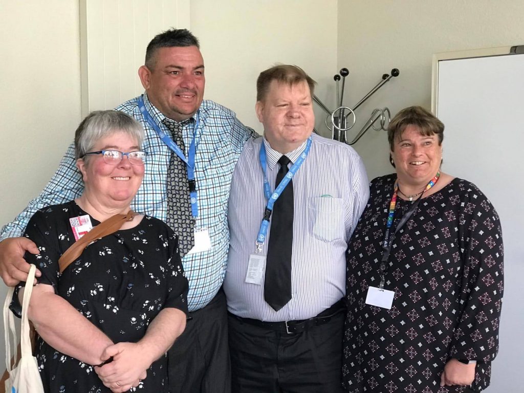 Four people posing for a photo, indoors.