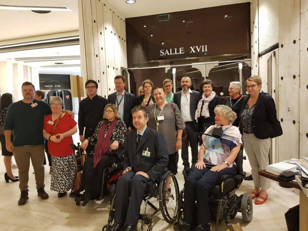 A group of people standing or sitting in wheelchairs, including the Australian civil society delegation and Ben Gauntlett.